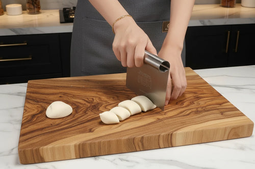 Person using a dough scraper  to shape dough on a cutting board.